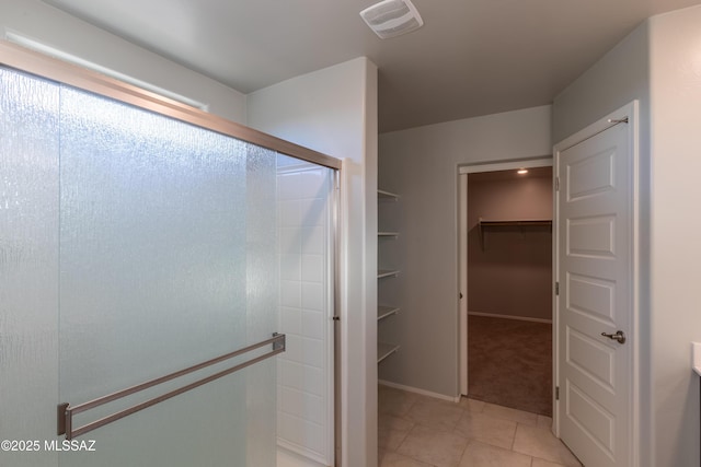full bathroom featuring tile patterned flooring, a walk in closet, visible vents, and a shower stall