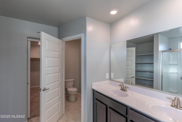 bathroom featuring double vanity, toilet, a sink, and tile patterned flooring