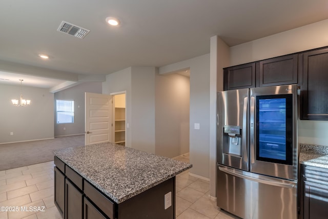kitchen with visible vents, a center island, stainless steel fridge with ice dispenser, stone countertops, and an inviting chandelier