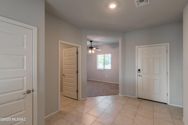 foyer entrance with light colored carpet, a ceiling fan, baseboards, light tile patterned floors, and visible vents