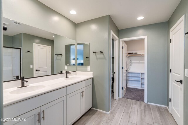 894 E Prairie Field Ln, Sahuarita, AZ 85629 - bathroom with double vanity, baseboards, a walk in closet, wood finished floors, and recessed lighting