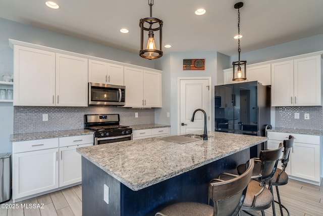 894 E Prairie Field Ln, Sahuarita, AZ 85629 - kitchen with appliances with stainless steel finishes, tasteful backsplash, a kitchen breakfast bar, white cabinetry, and hanging light fixtures