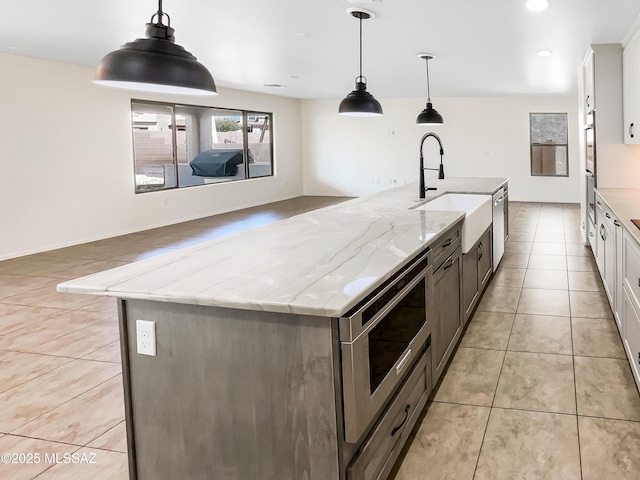 11155 E Vail Vista Ct, Tucson, AZ 85747 - kitchen with stainless steel microwave, a kitchen island with sink, light stone countertops, a sink, and white cabinets