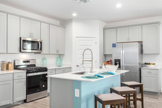 kitchen with recessed lighting, appliances with stainless steel finishes, a sink, light wood-type flooring, and a kitchen breakfast bar
