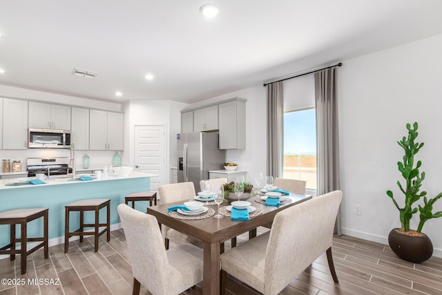 dining area featuring baseboards, visible vents, wood tiled floor, and recessed lighting