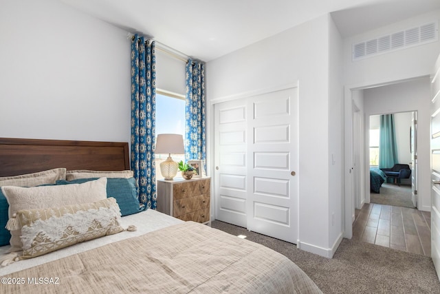 carpeted bedroom featuring baseboards, visible vents, and a closet
