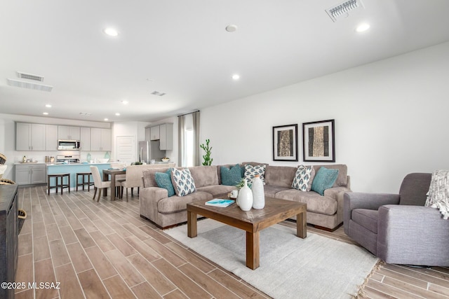 living area featuring recessed lighting, visible vents, and light wood-type flooring