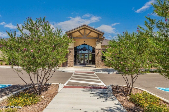 property entrance with stone siding, stucco siding, and french doors