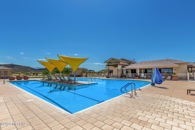 pool featuring a patio, a mountain view, and fence
