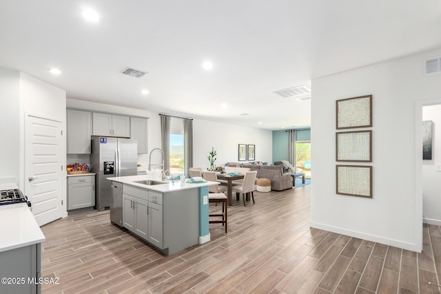 kitchen featuring visible vents, gray cabinetry, light wood-type flooring, and a sink