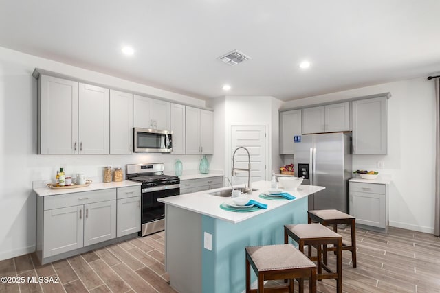 kitchen with visible vents, gray cabinets, stainless steel appliances, and a sink