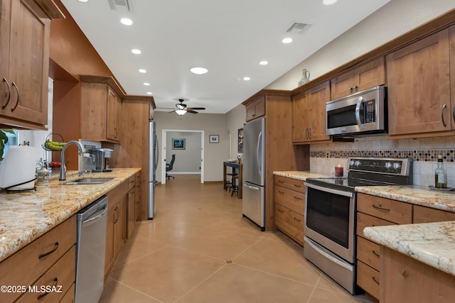 kitchen featuring a sink, appliances with stainless steel finishes, ceiling fan, and backsplash