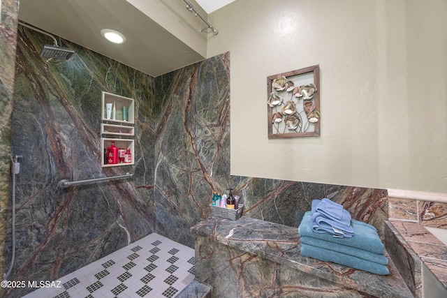 bathroom featuring a marble finish shower and tile walls
