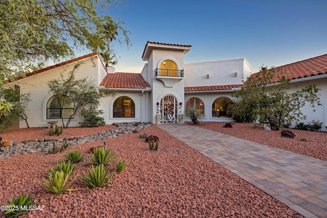 mediterranean / spanish house featuring a tiled roof, driveway, a balcony, and stucco siding
