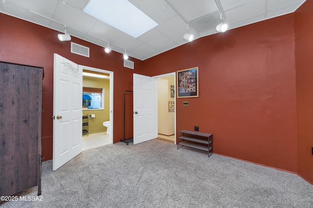 spare room featuring carpet floors, rail lighting, and visible vents