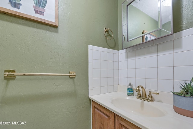bathroom with vanity, a textured wall, and decorative backsplash