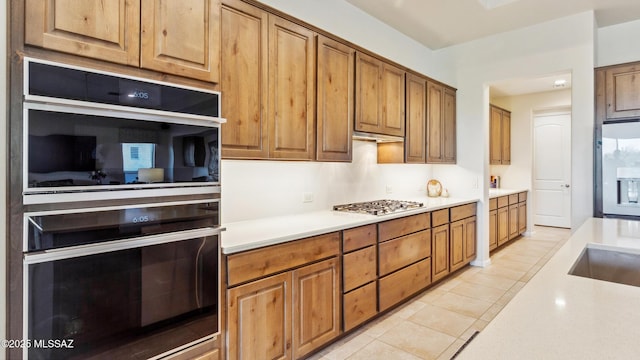2230 E Thunder Bluff Dr, Green Valley, AZ 85614 - kitchen with light countertops, stainless steel gas stovetop, light tile patterned flooring, and brown cabinetry