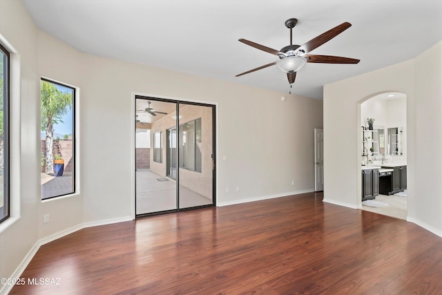 4706 W Cholla Bluff Dr, Marana, AZ 85658 - empty room featuring a ceiling fan, wood finished floors, arched walkways, and baseboards