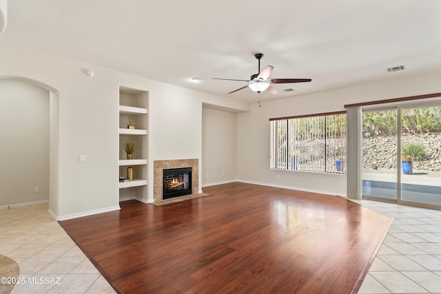 4706 W Cholla Bluff Dr, Marana, AZ 85658 - unfurnished living room with built in shelves, light tile patterned flooring, a ceiling fan, baseboards, and a tile fireplace
