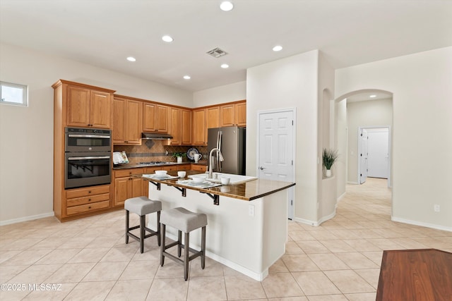 4706 W Cholla Bluff Dr, Marana, AZ 85658 - kitchen featuring appliances with stainless steel finishes, a sink, arched walkways, light tile patterned flooring, and backsplash