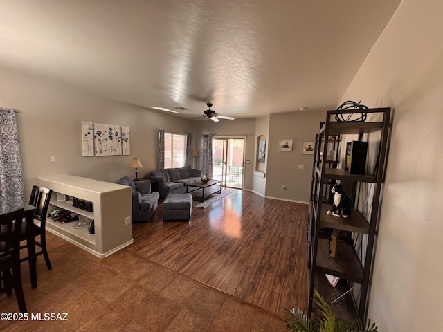 living area featuring baseboards and a ceiling fan