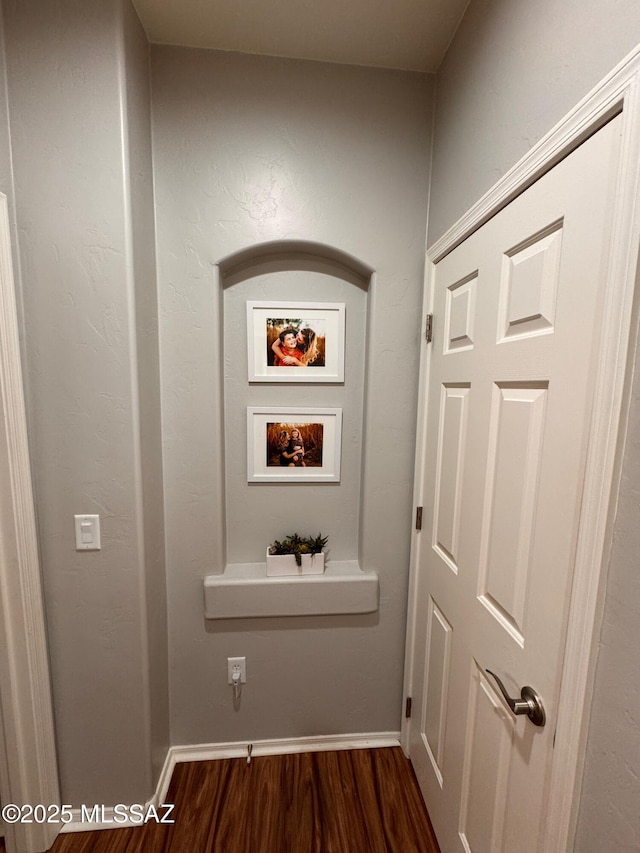 corridor with dark wood finished floors and baseboards