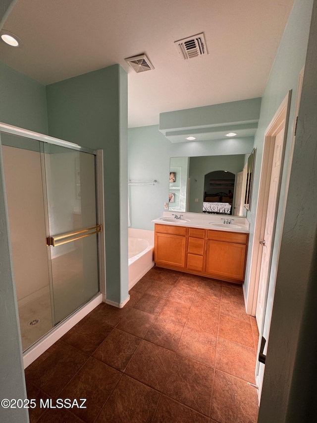 ensuite bathroom with visible vents, a garden tub, a stall shower, and a sink