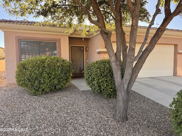 view of front of house with stucco siding, concrete driveway, and an attached garage