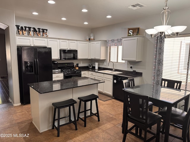 kitchen with visible vents, a kitchen island, black appliances, recessed lighting, and a notable chandelier