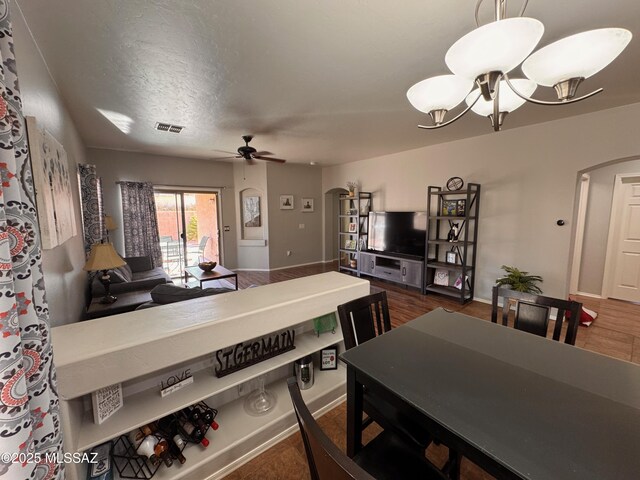 dining area with arched walkways, ceiling fan with notable chandelier, and baseboards