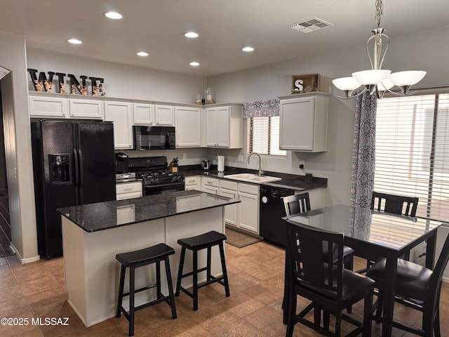 kitchen with an inviting chandelier, a sink, black appliances, visible vents, and a kitchen island
