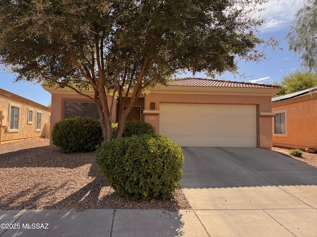 view of front of home featuring stucco siding, driveway, a tiled roof, and an attached garage