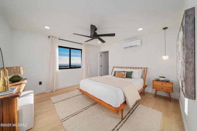bedroom featuring a wall unit AC, light wood finished floors, and recessed lighting