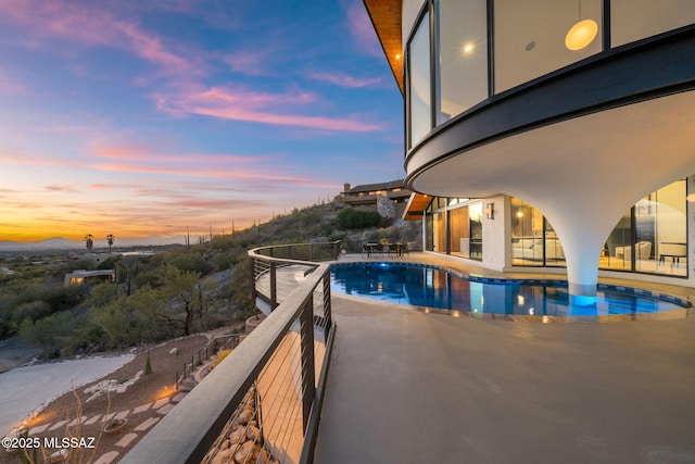 pool at dusk featuring a patio and a fenced in pool