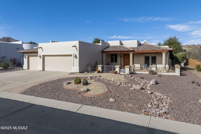 view of front of home with a garage, stucco siding, a tiled roof, and driveway