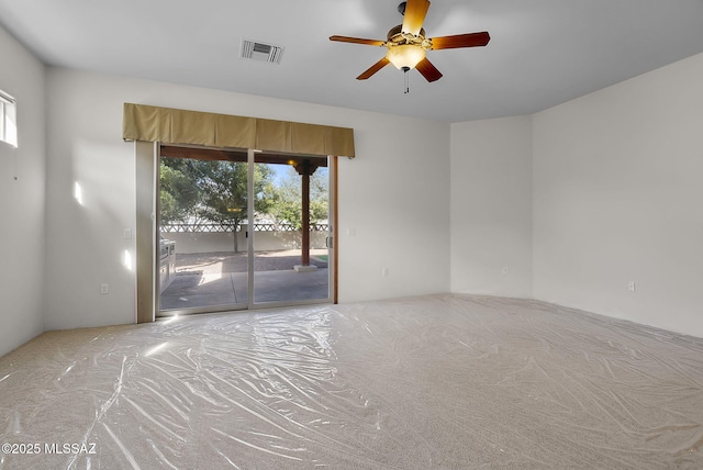 carpeted empty room with a ceiling fan and visible vents
