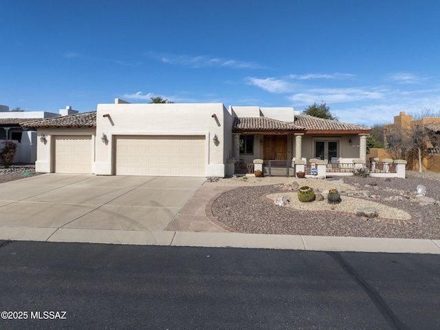 view of front of property featuring covered porch, stucco siding, a tiled roof, an attached garage, and driveway