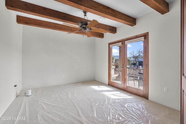 carpeted spare room featuring french doors, beamed ceiling, and a ceiling fan