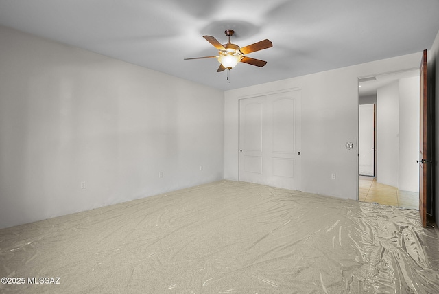 unfurnished bedroom with a closet, a ceiling fan, and carpet flooring