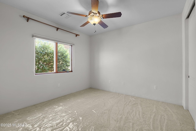 carpeted empty room with a ceiling fan and visible vents