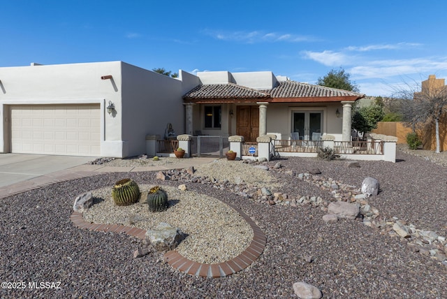view of front of property featuring covered porch, a tiled roof, french doors, an attached garage, and stucco siding
