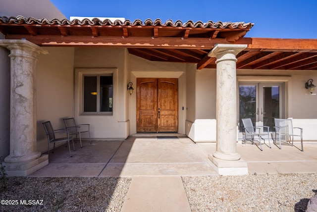 view of exterior entry with a patio, french doors, and stucco siding
