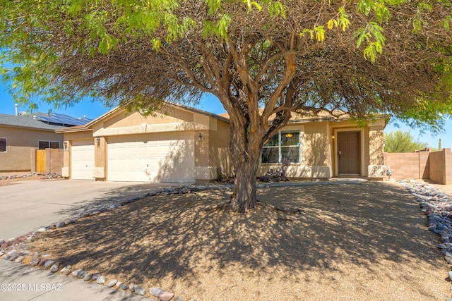 ranch-style house featuring a garage, fence, stucco siding, driveway, and solar panels