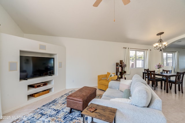 living area featuring baseboards, vaulted ceiling, light tile patterned floors, and ceiling fan with notable chandelier