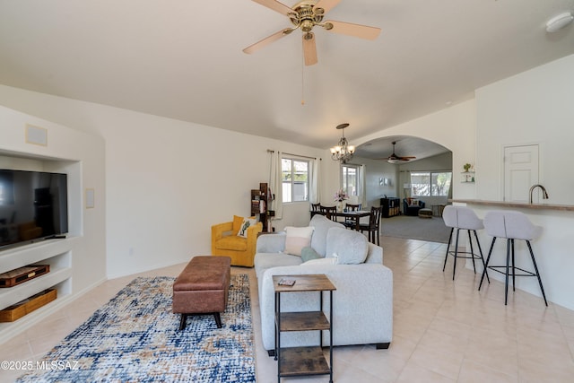 living area featuring arched walkways, lofted ceiling, light tile patterned floors, and ceiling fan with notable chandelier