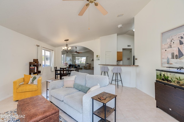 living room with arched walkways, lofted ceiling, light tile patterned flooring, and ceiling fan with notable chandelier