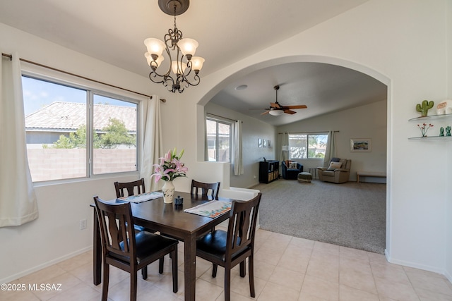 dining area featuring lofted ceiling, baseboards, light colored carpet, arched walkways, and ceiling fan with notable chandelier