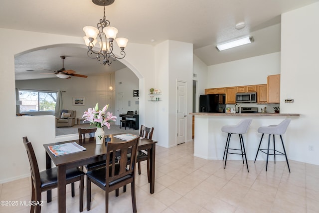 dining space featuring light tile patterned floors, arched walkways, ceiling fan with notable chandelier, and lofted ceiling