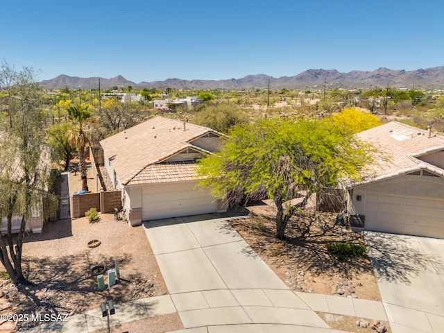 view of front of property featuring fence, stucco siding, an attached garage, a mountain view, and driveway