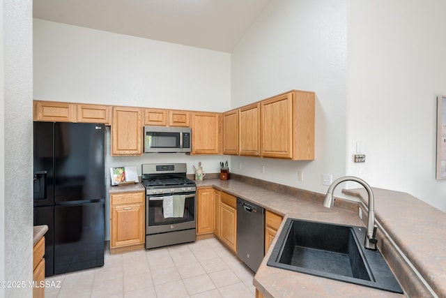 kitchen with light tile patterned flooring, light brown cabinets, high vaulted ceiling, a sink, and appliances with stainless steel finishes